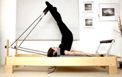 Legs in straps on a wooden reformer in the studio